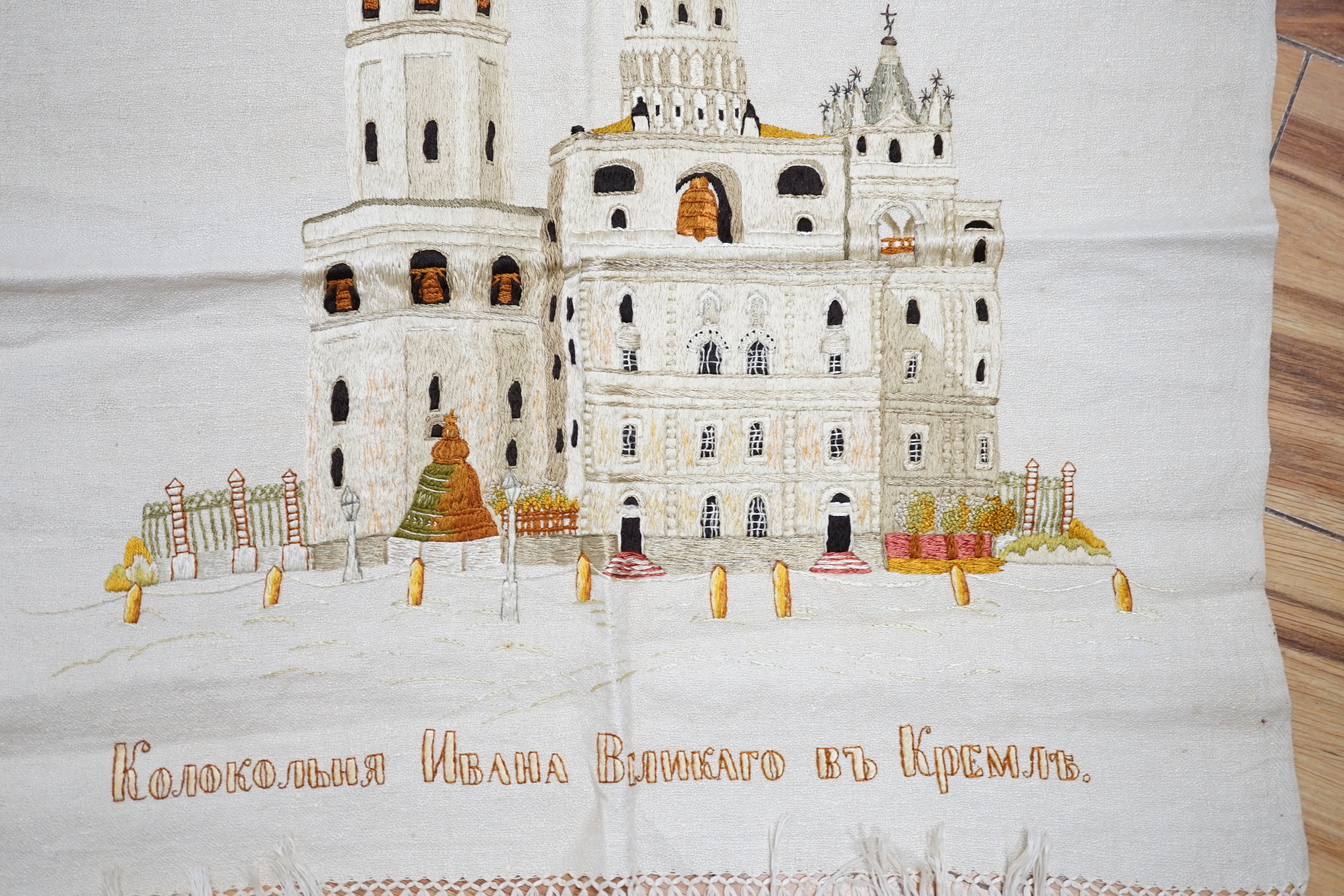 A Russian silk embroidery of a building with embroidered text below: translation ‘Ivan the Greats Belltower, The Kremlin’, 56cm high not including fringe